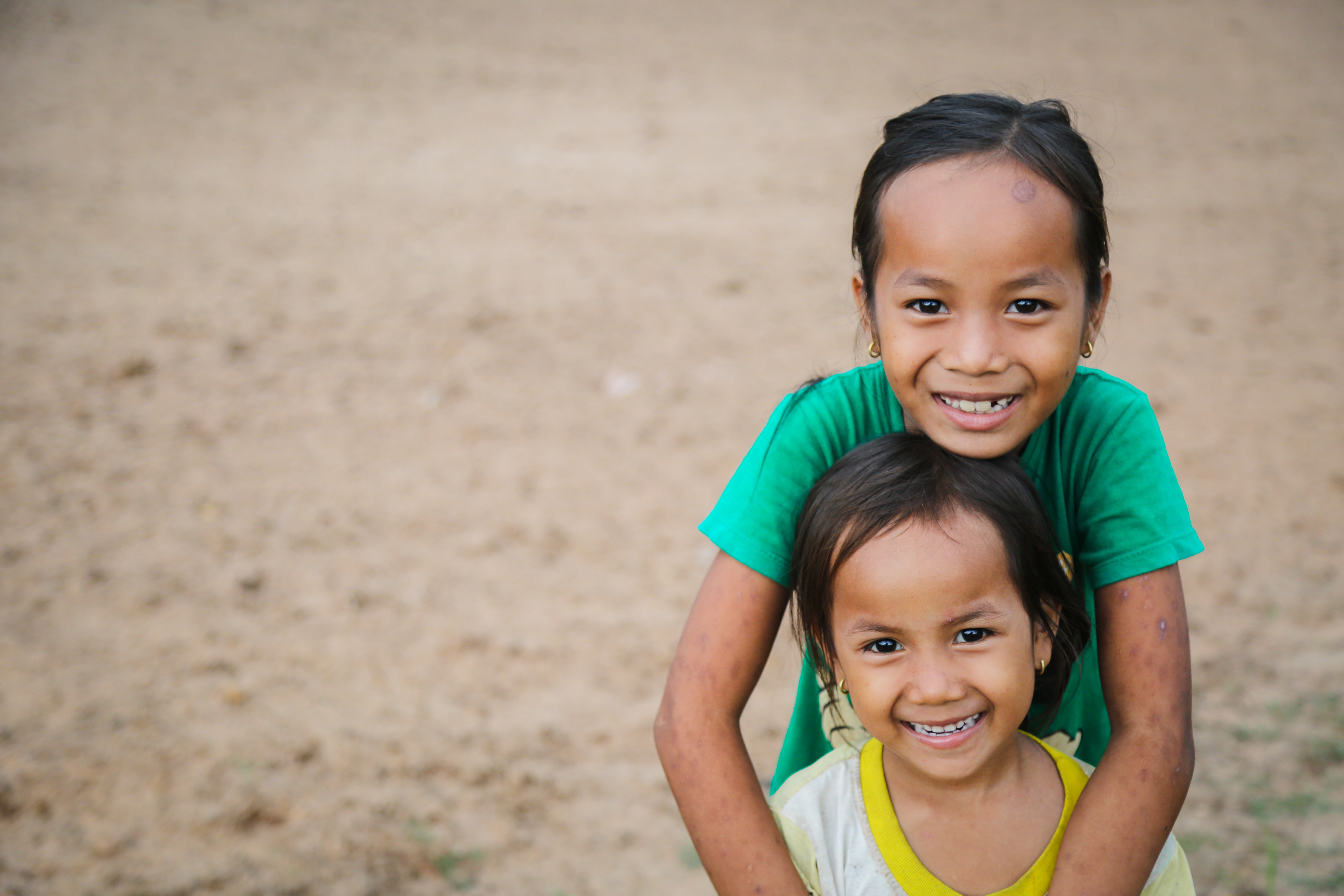 Two sisters hug out the front of their home in Cambodia