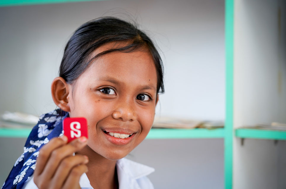 Nita smiling and holding a small token with a letter on it.